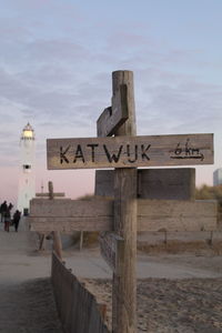 Text on wooden post against sky