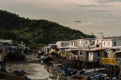 Boats moored by buildings in city against sky