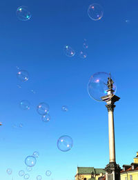 Low angle view of bubbles with monument against blue sky