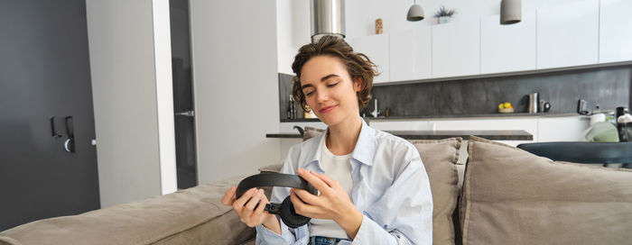 Young woman using phone while sitting on sofa at home