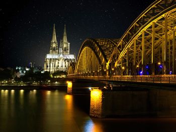 Illuminated bridge over river at night