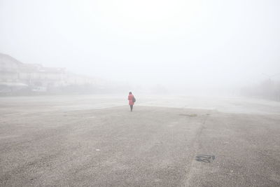 Woman standing at beach during foggy weather