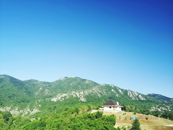 Scenic view of house and mountains against clear blue sky