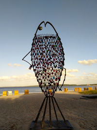 Ferris wheel on beach against sky during sunset