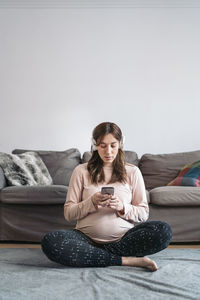 Pregnant woman using smart phone at home
