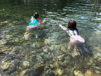 Rear view of people swimming in lake