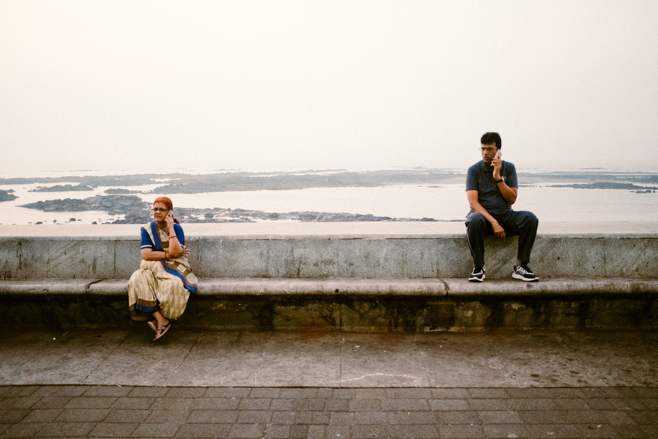 full length, water, sitting, real people, two people, leisure activity, togetherness, lifestyles, men, sea, casual clothing, sky, people, women, nature, young adult, clear sky, young women, adult, outdoors, couple - relationship