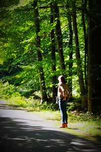 Full length of woman standing on road in forest