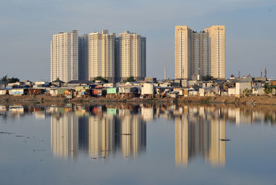 Reflection of buildings in lake against clear sky