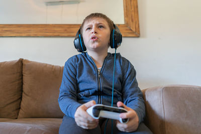 Teenage boy using mobile phone while sitting on sofa at home
