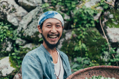 Portrait of smiling man holding basket while standing against rocks