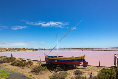 Boat moored on beach against sky