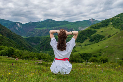 Rear view of man standing on landscape against mountain range