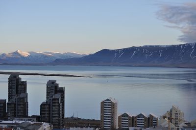 Scenic view of lake by snowcapped mountains against sky