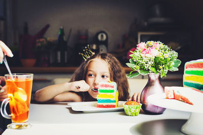 Portrait of woman holding food while sitting on table