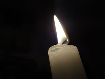 Close-up of illuminated candle in darkroom