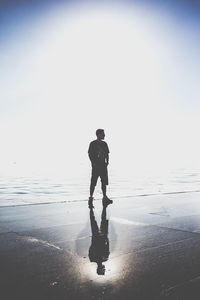 Silhouette man standing on beach against clear sky