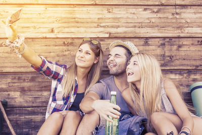 Friends sitting on wooden wall