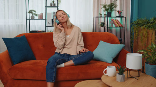 Young woman sitting on sofa at home