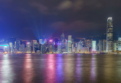 Illuminated city by buildings against sky at night