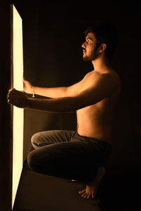 Side view of young man looking at camera