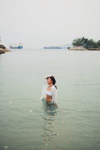 Young woman standing in sea against clear sky