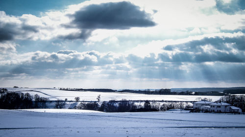 Snow covered landscape against cloudy sky