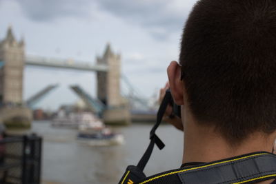 Close-up of man against river and bridge in city