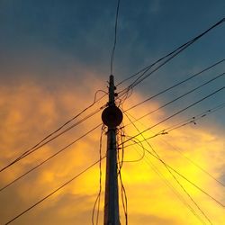 Low angle view of silhouette electricity pylon against sky during sunset