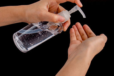 Close-up of person holding hands over black background