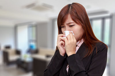 Businesswoman suffering from cold while standing in office