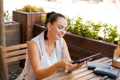 Beautiful businesswoman with smile sitting with touchpad in cozy restaurant