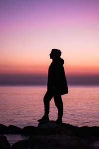 Silhouette man standing on beach against sky during sunset