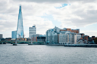 City at waterfront against cloudy sky