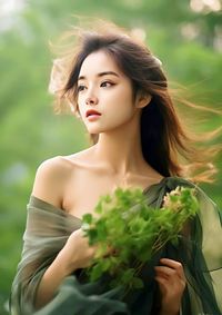 Portrait of beautiful young woman standing against plants