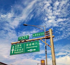 Low angle view of information sign against cloudy sky