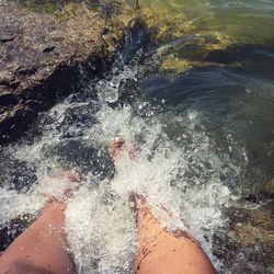 Low section of person splashing water at sea shore