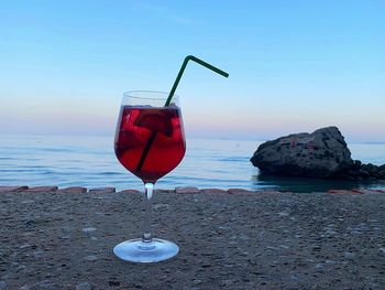 Red wine on rock at beach against sky