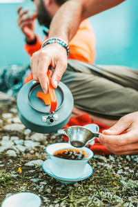 Low section of man pouring tea while sitting at beach