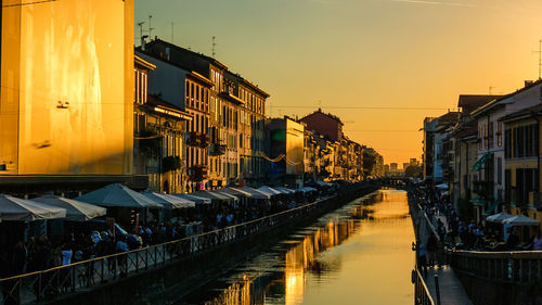 Canal amidst buildings in city during sunset