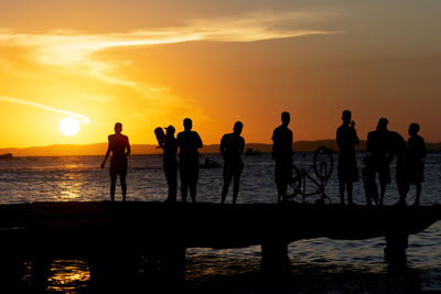 Silhouette of young people jumping from the crush bridge at the yellow sunset.