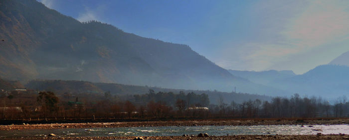 Scenic view of lake by mountains against sky