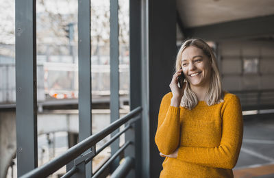 Smiling businesswoman talking on mobile phone in parking garage