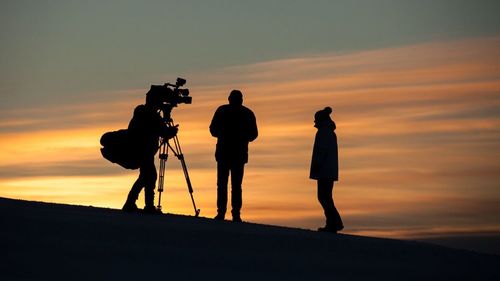 Silhouette of photographing against sky during sunset