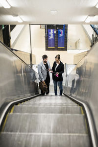 Full length of business colleagues on escalator in subway station