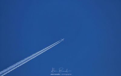 Low angle view of vapor trail against blue sky