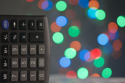 Close-up of calculator against defocused multi colored lights