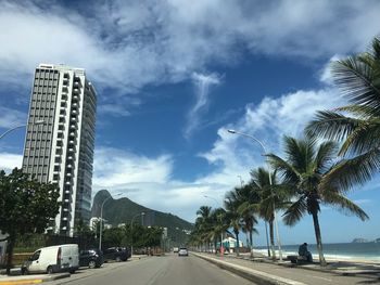 Road by buildings against sky in city