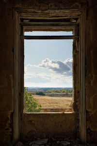 Cloudy landscape framed by a broken window