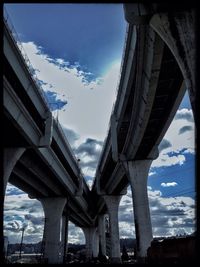 Low angle view of bridge against cloudy sky